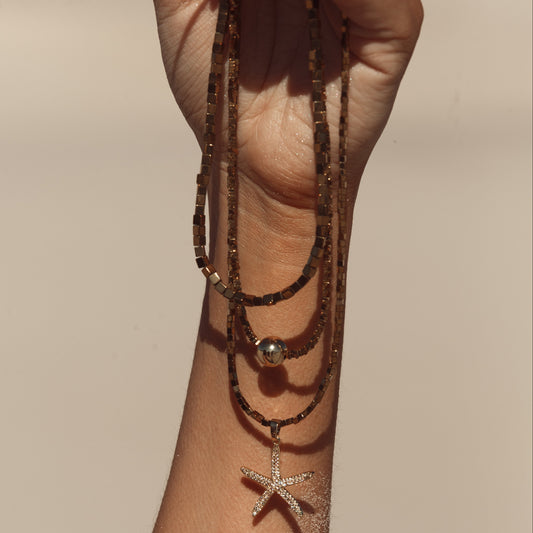 Colar Hematita com Pingente Estrela do Mar Cravejado Dourado